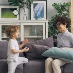 a woman sitting on top of a couch next to a little boy